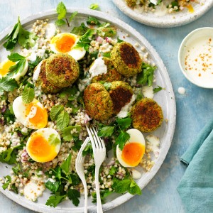 Baked falafel on plate with salad, fresh herbs and eggs